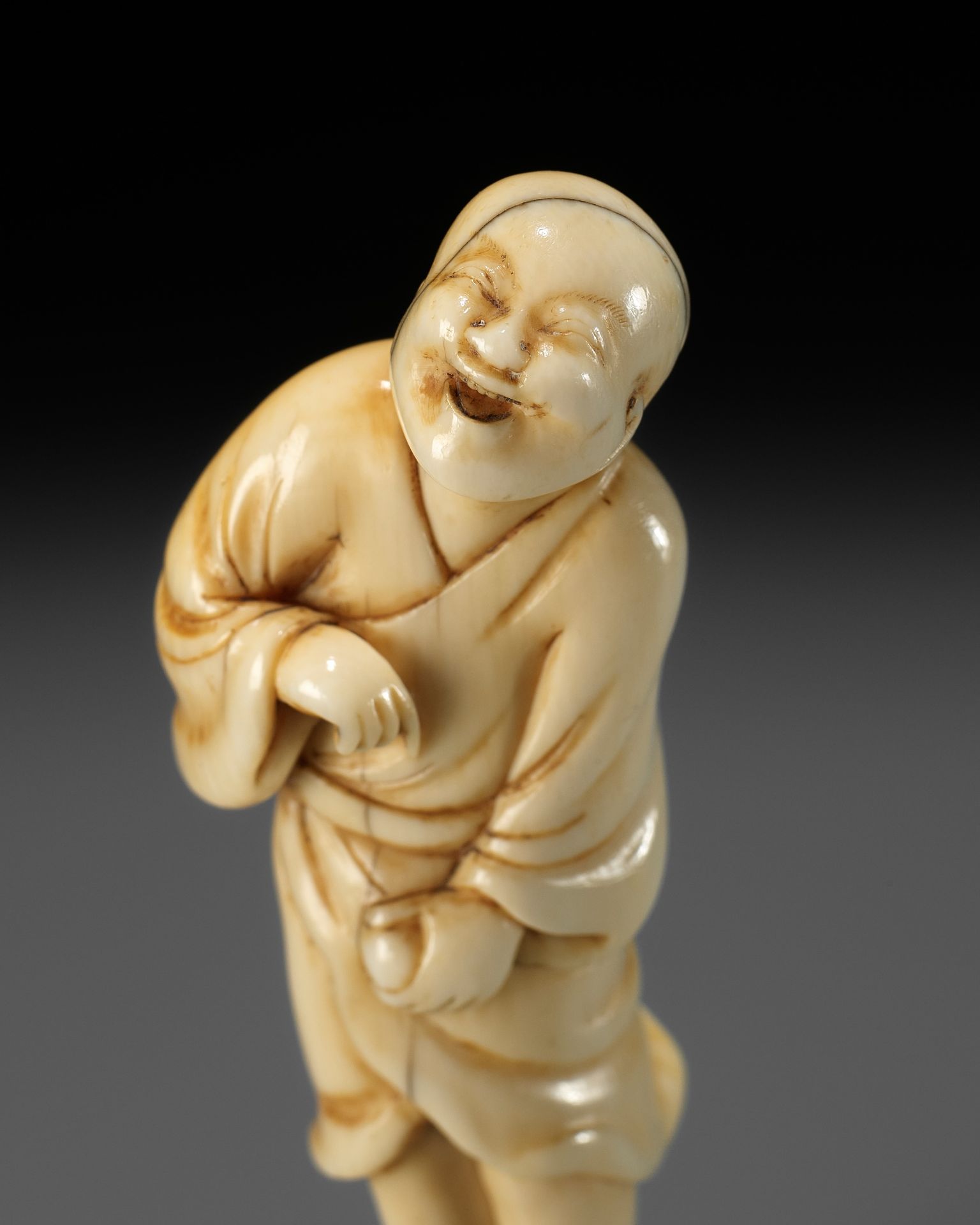 AN EARLY OSAKA SCHOOL IVORY NETSUKE OF A LAUGHING EGG-TESTER