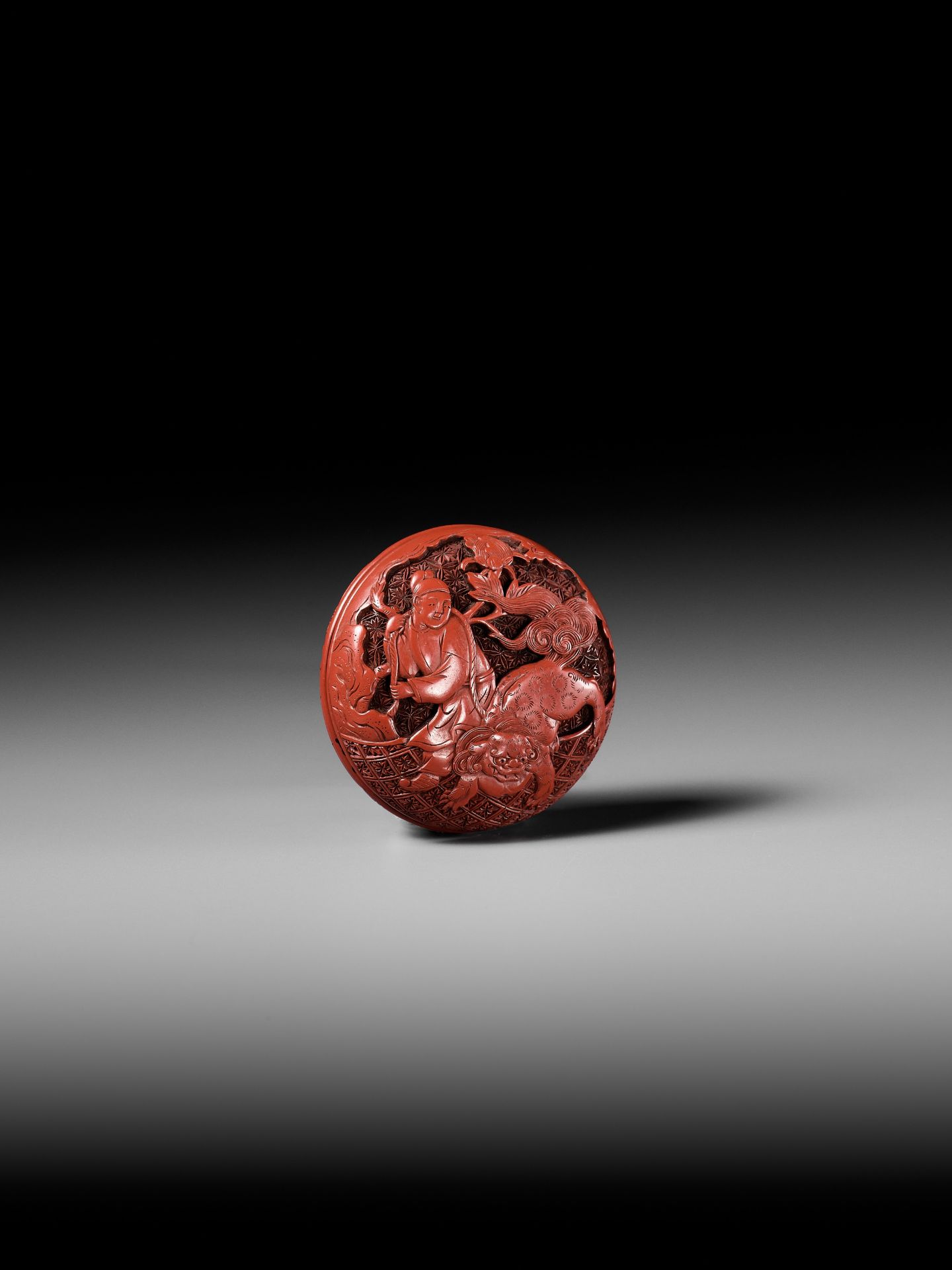 A FINE TSUISHU (CARVED RED LACQUER) MANJU NETSUKE WITH CHINESE LITERATI AND SHISHI - Image 5 of 9