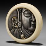 AN IVORY KAGAMIBUTA NETSUKE DEPICTING PILGRIMS CLIMBING THE GREAT BUDDHA OF NARA