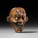 A PALE BOXWOOD KYOGEN MASK NETSUKE OF A GROTESQUE FOREIGNER, ATTRIBUTED TO KOKEISAI SANSHO