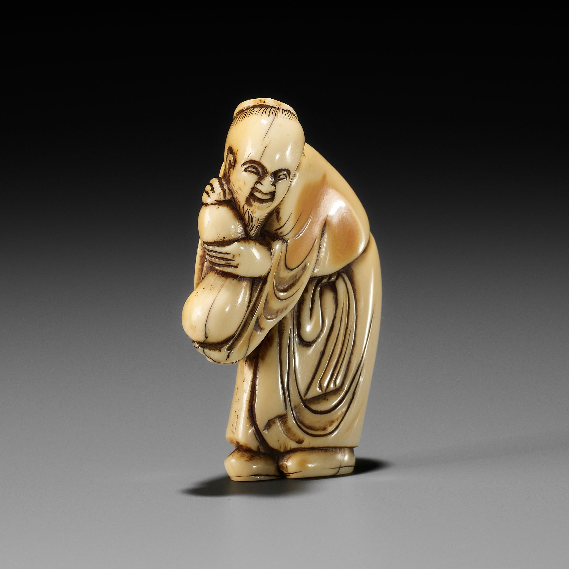 AN EARLY IVORY NETSUKE OF A CHINESE IMMORTAL WITH A GOURD