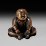 A CHARMING EDO SCHOOL WOOD NETSUKE OF A SEATED BOY