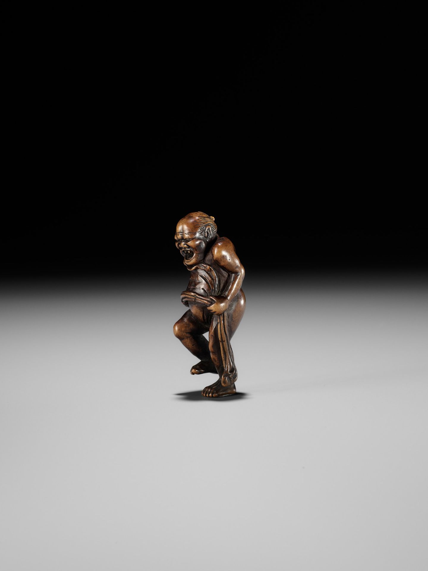 TOUN: AN AMUSING WOOD NETSUKE OF A NAKED MAN TYING HIS FUNDOSHI - Image 4 of 11