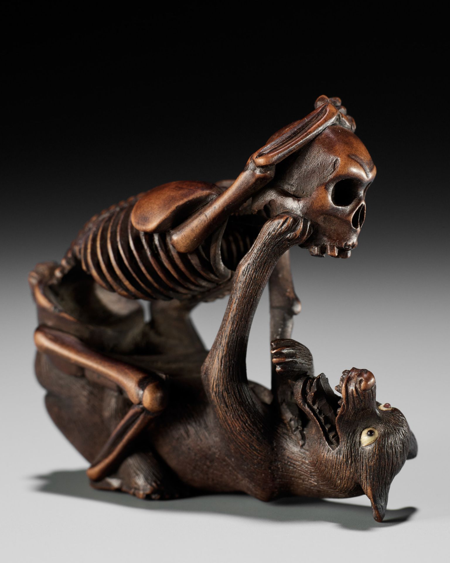 A FINE WOOD NETSUKE OF A WOLF AND SKELETON, ATTRIBUTED TO SHOKO SUGONOYA