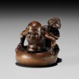 MINKOKU: A FINE AND HUMOROUS WOOD NETSUKE OF AN ONI BATHING A RAKAN