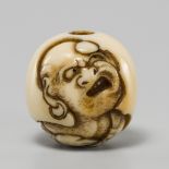 DOSHO: A FINE IVORY OJIME DEPICTING DARUMA WITH A TANKOBU