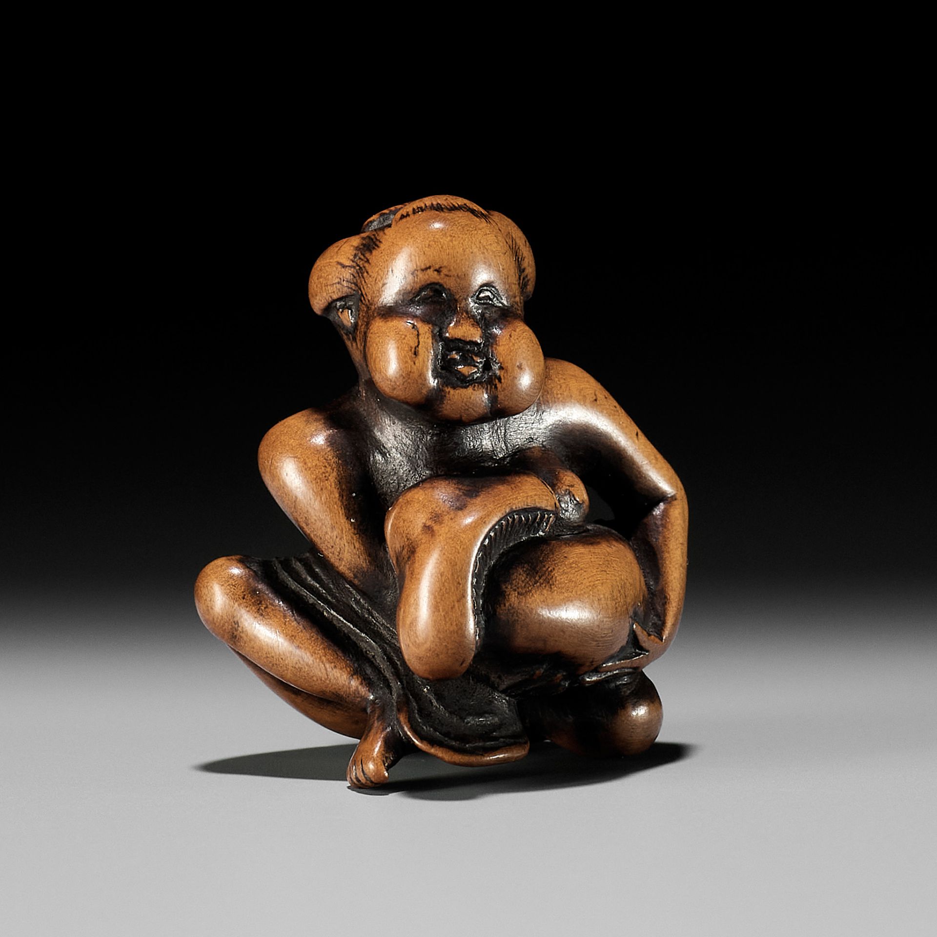 A WOOD SHUNGA NETSUKE OF OKAME CRADLING A HUGE MUSHROOM