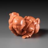 RYUHO: A VERY RARE SOLID CORAL NETSUKE OF A BOY AND CAT