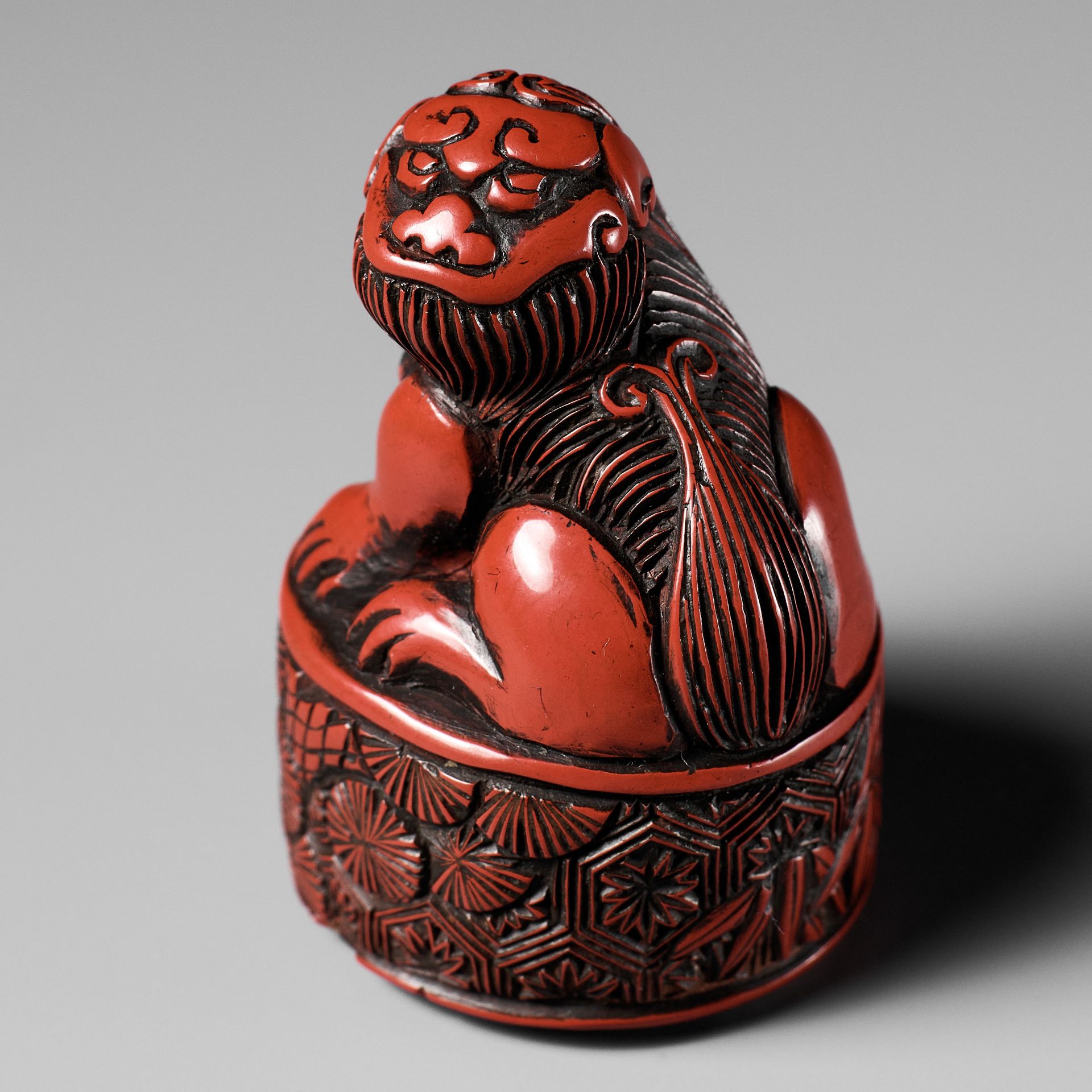 A RARE TSUISHU (CARVED RED LACQUER) INGYO (SEAL) NETSUKE OF A SHISHI