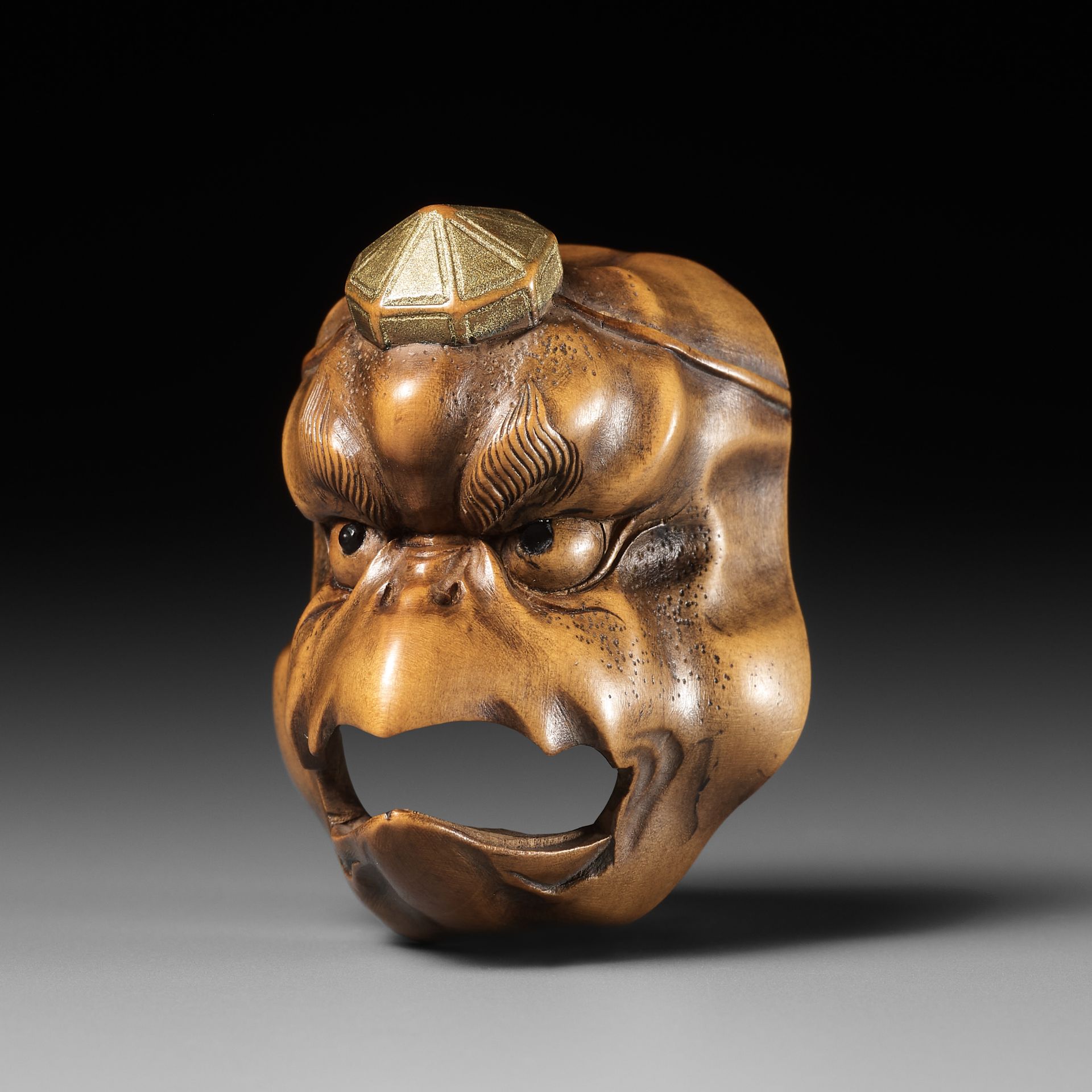 A PALE BOXWOOD MASK NETSUKE OF A KARASU TENGU, ATTRIBUTED TO KOKEISAI SANSHO