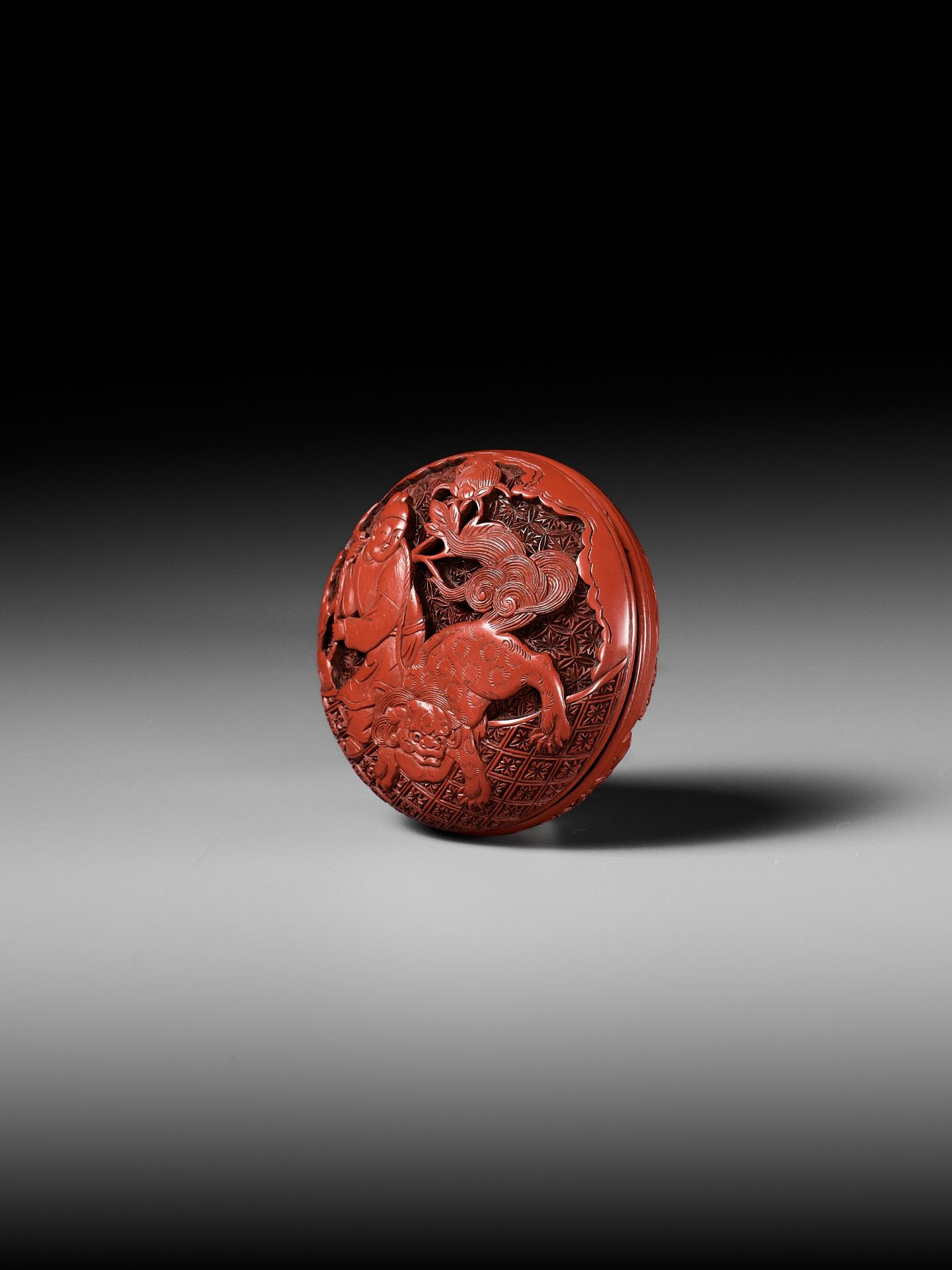A FINE TSUISHU (CARVED RED LACQUER) MANJU NETSUKE WITH CHINESE LITERATI AND SHISHI - Image 2 of 9
