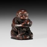 BUNCHO: A FINE WOOD NETSUKE OF A MONKEY EATING PERSIMMONS