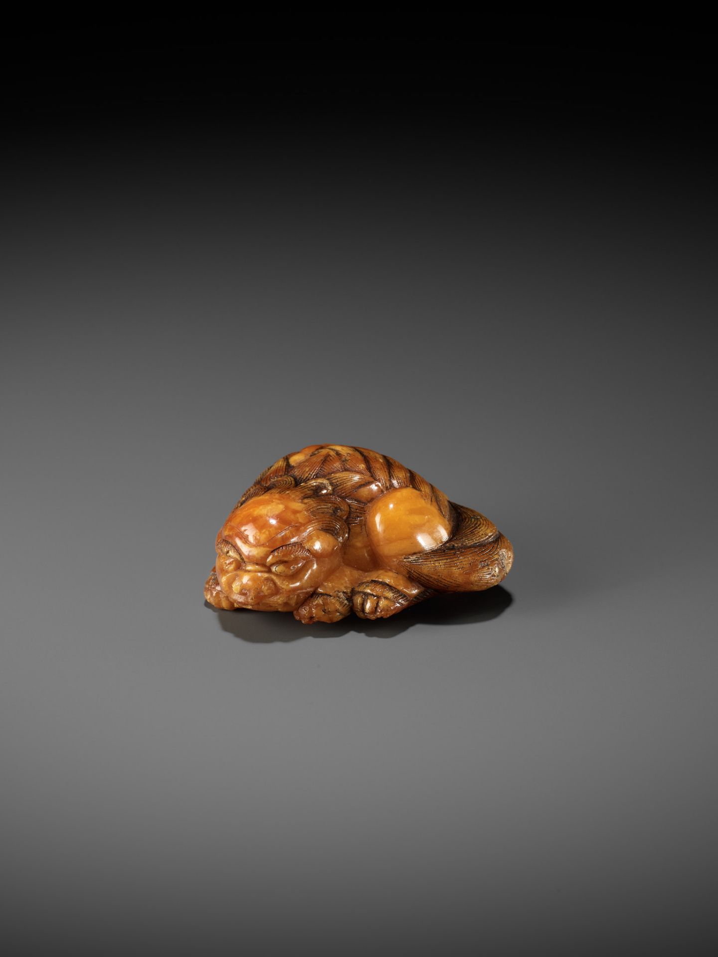 A VERY RARE CLOUDY AMBER NETSUKE OF A RECUMBENT SHISHI - Bild 2 aus 9