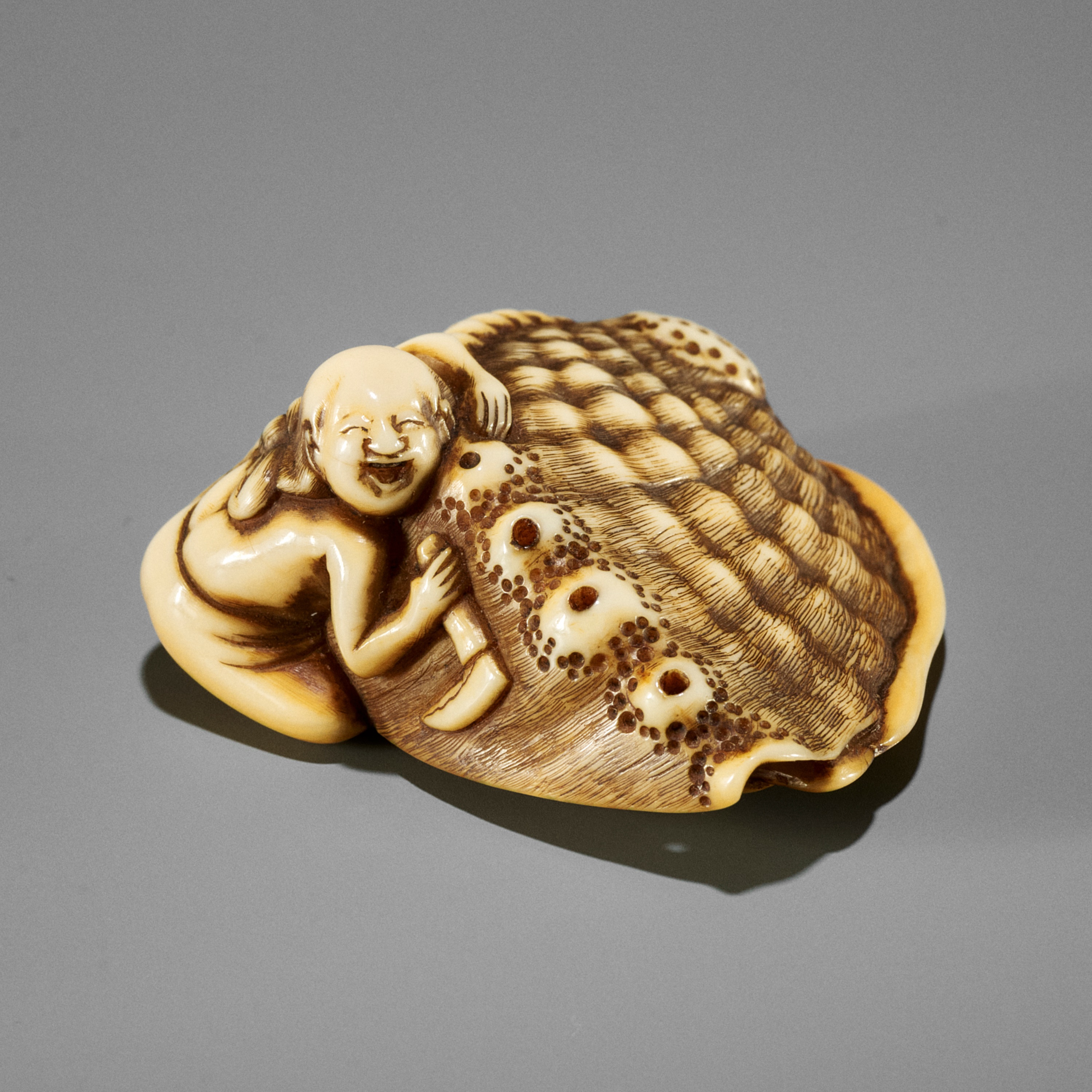 GARAKU: A SUPERB IVORY NETSUKE OF A FISHER GIRL WITH GIANT AWABI