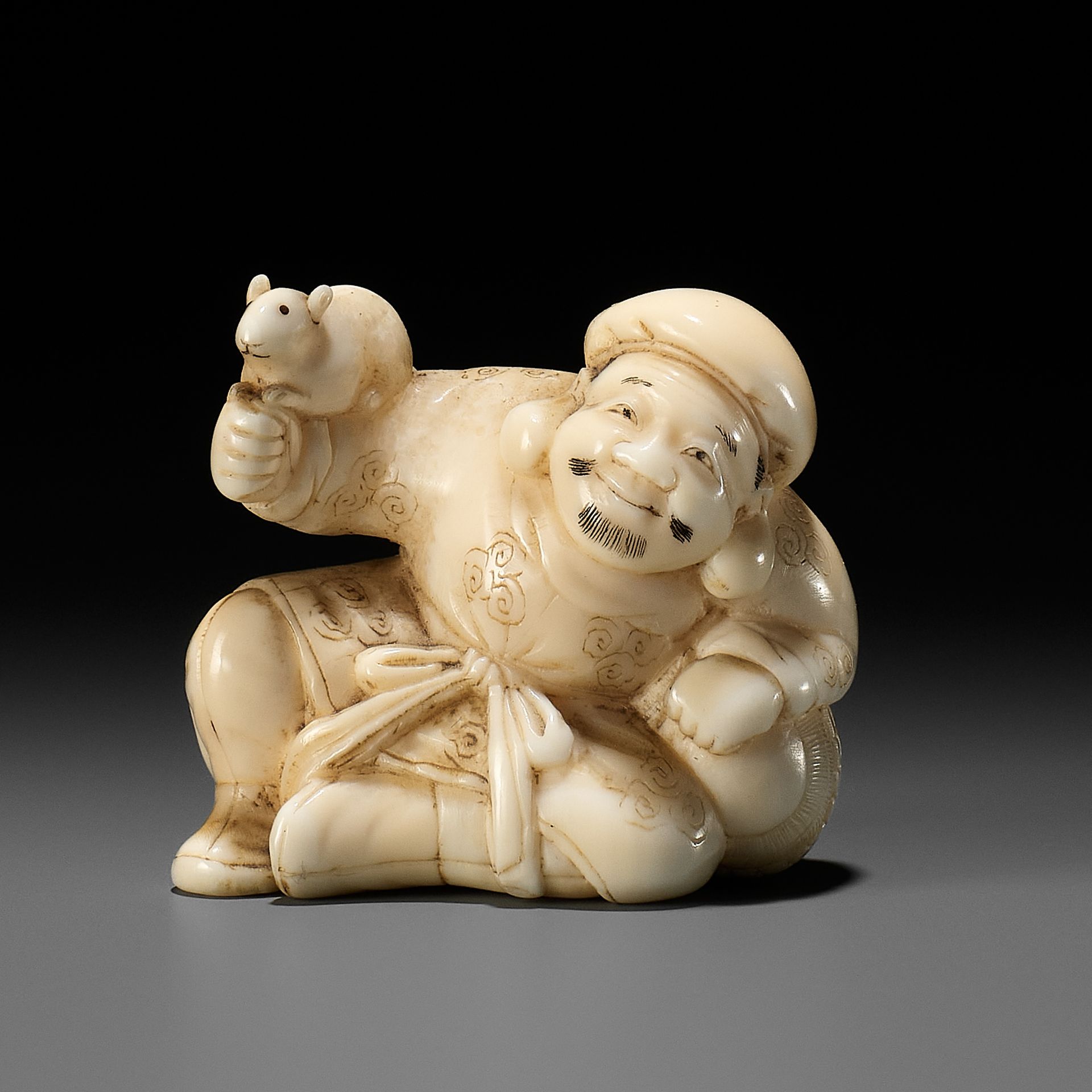 A FINE WALRUS TUSK NETSUKE OF DAIKOKU HOLDING A RAT