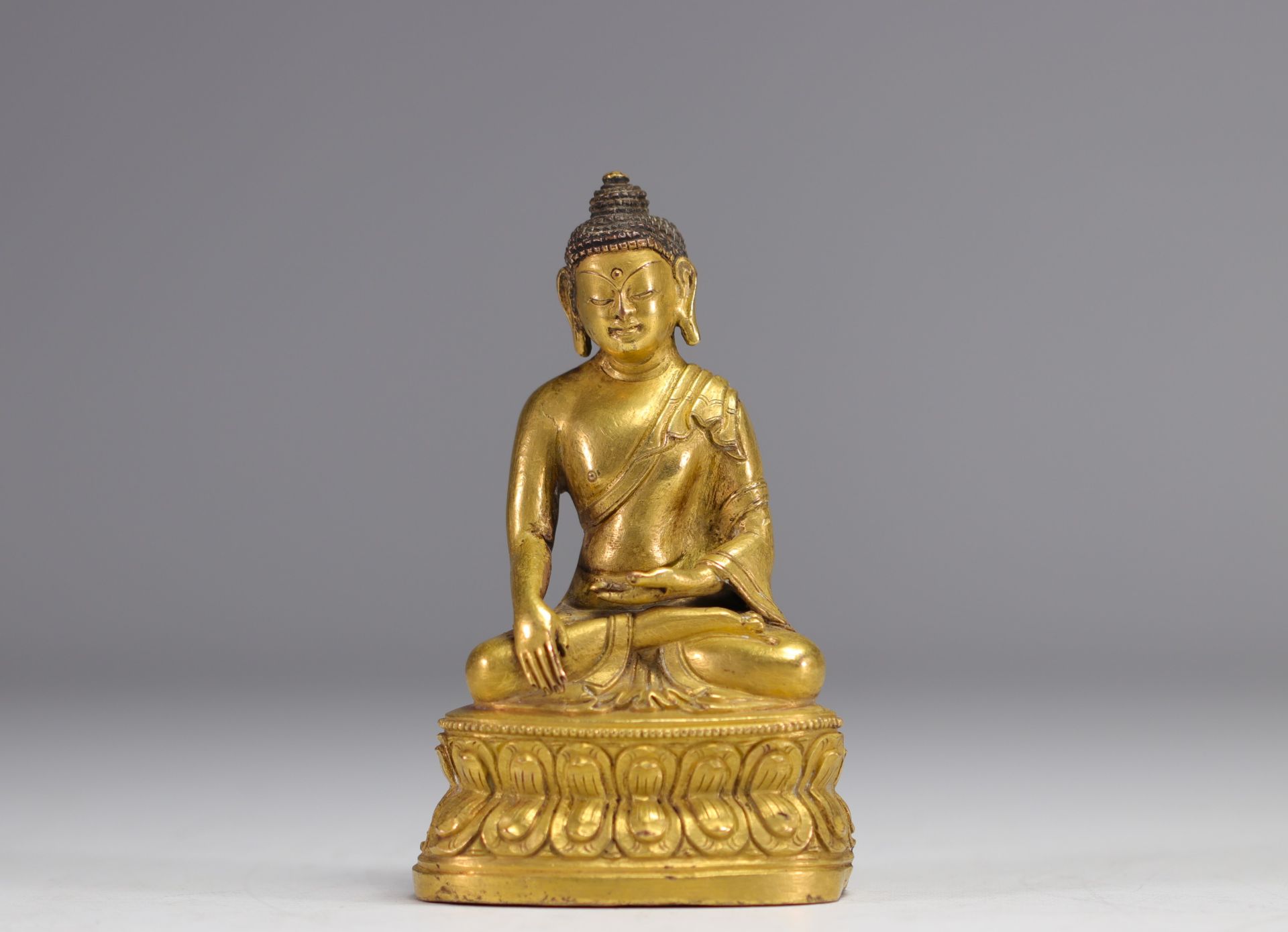 Sculpture of a seated Buddha on a gilded bronze base