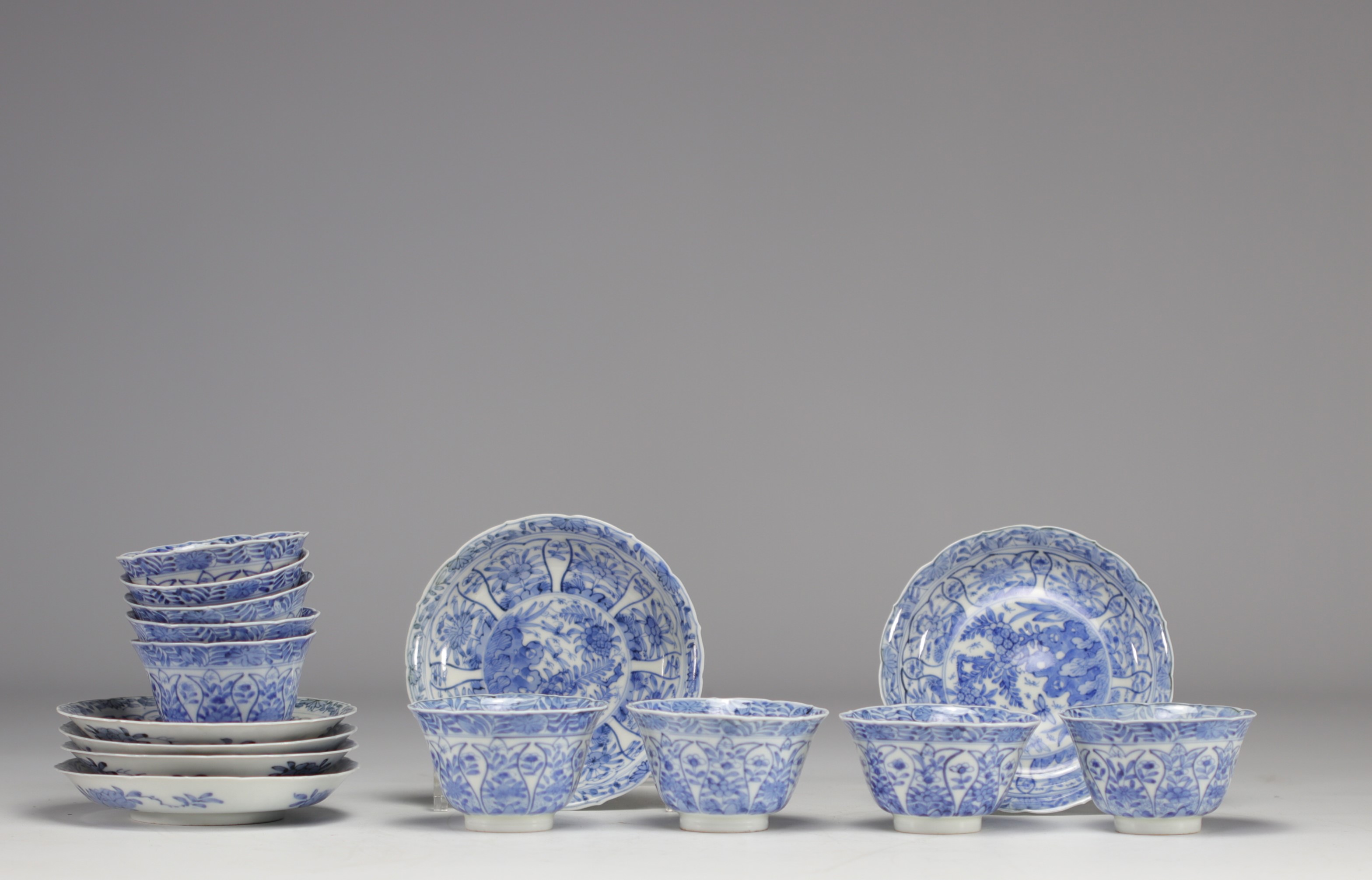 Set of white and blue bowls and saucers with various flower decorations from 18th century
