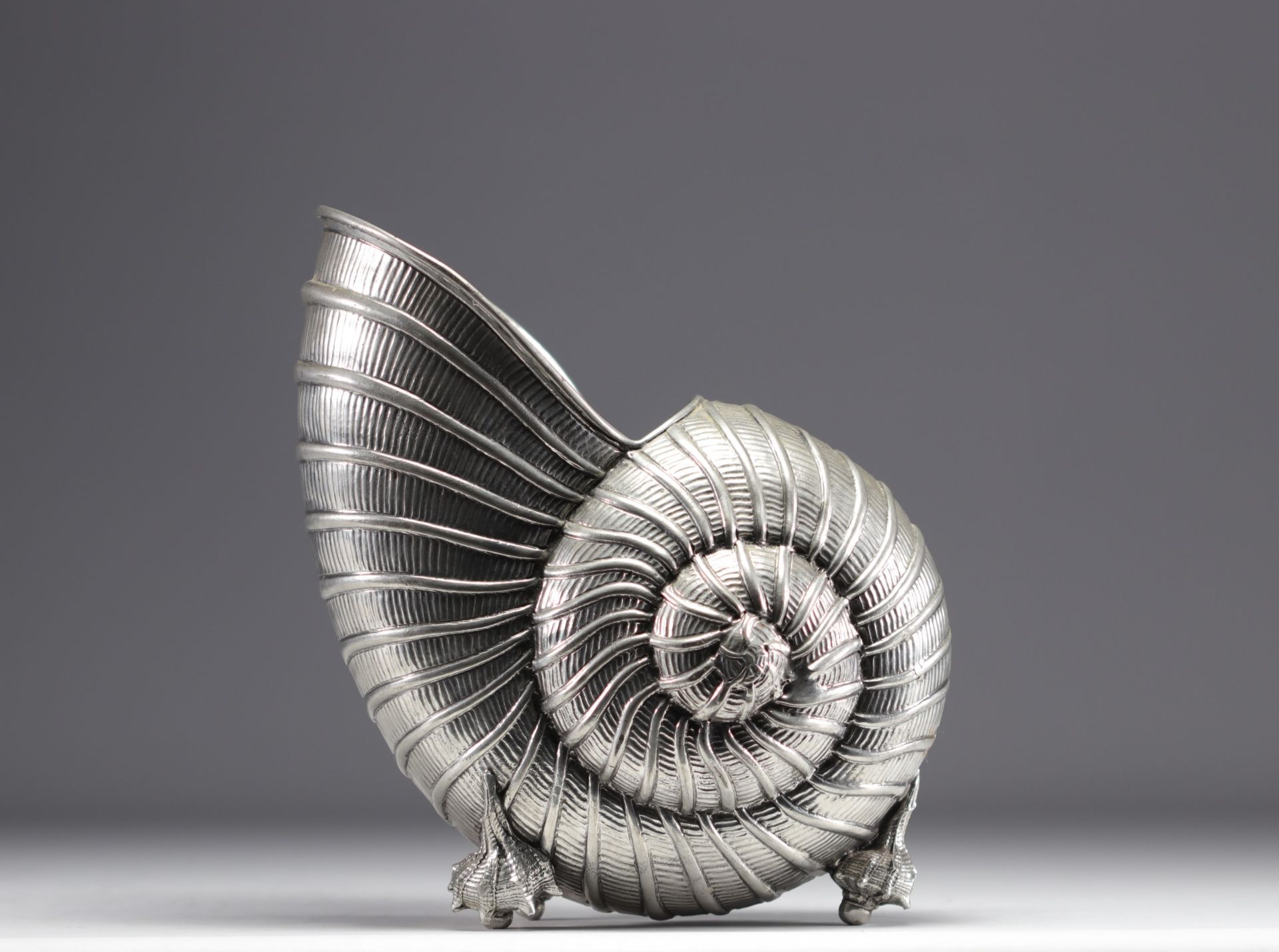 Nautilus-shaped champagne bucket on four small shell feet.