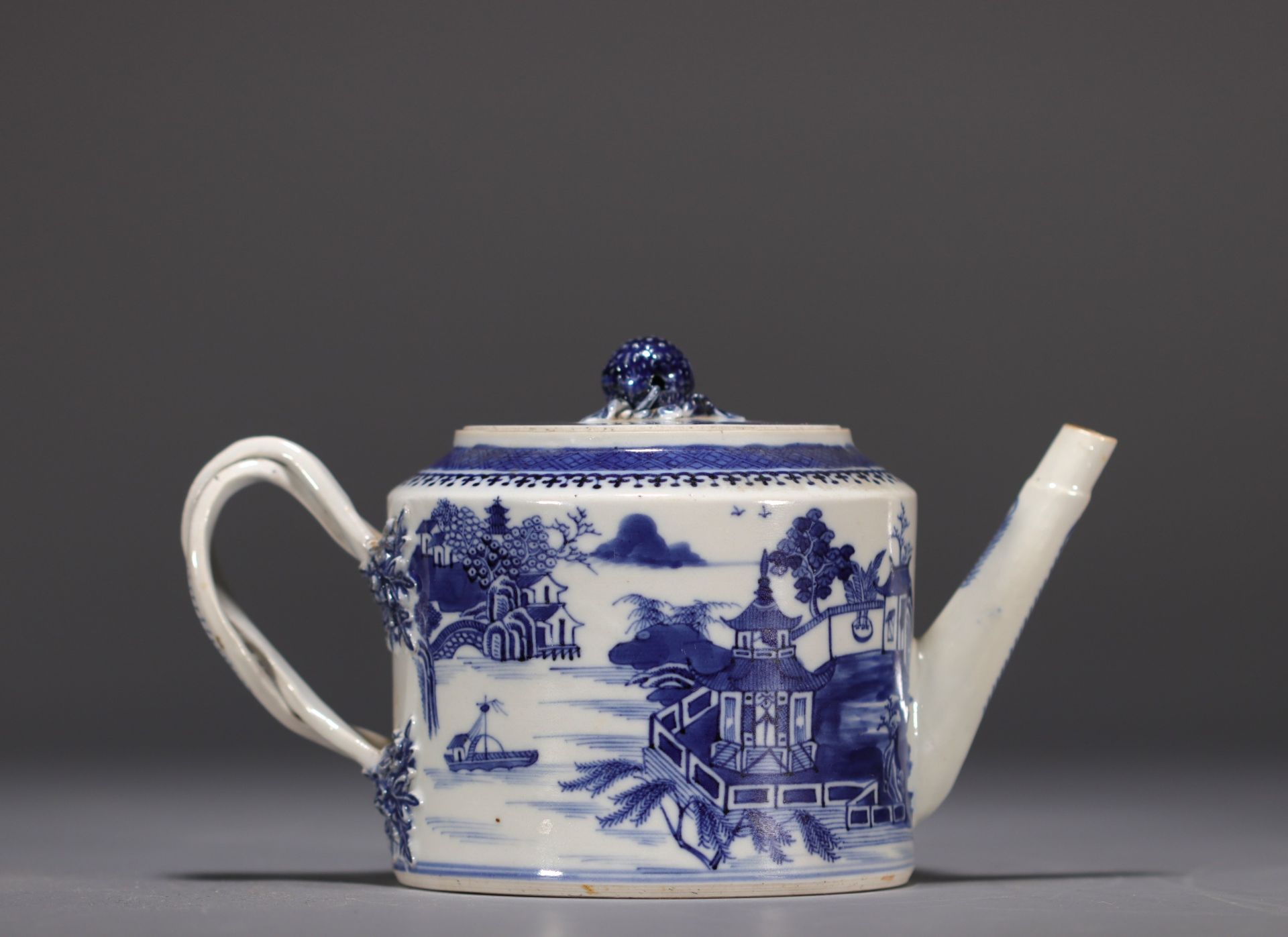China - A white and blue porcelain teapot decorated with landscapes and a junk, 18th century.