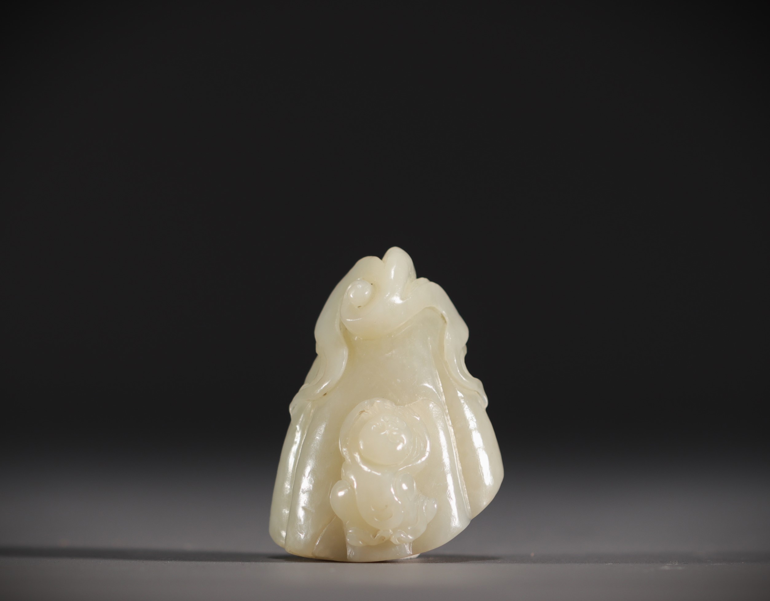 China - White jade pendant in the shape of a fruit surmounted by a young child.