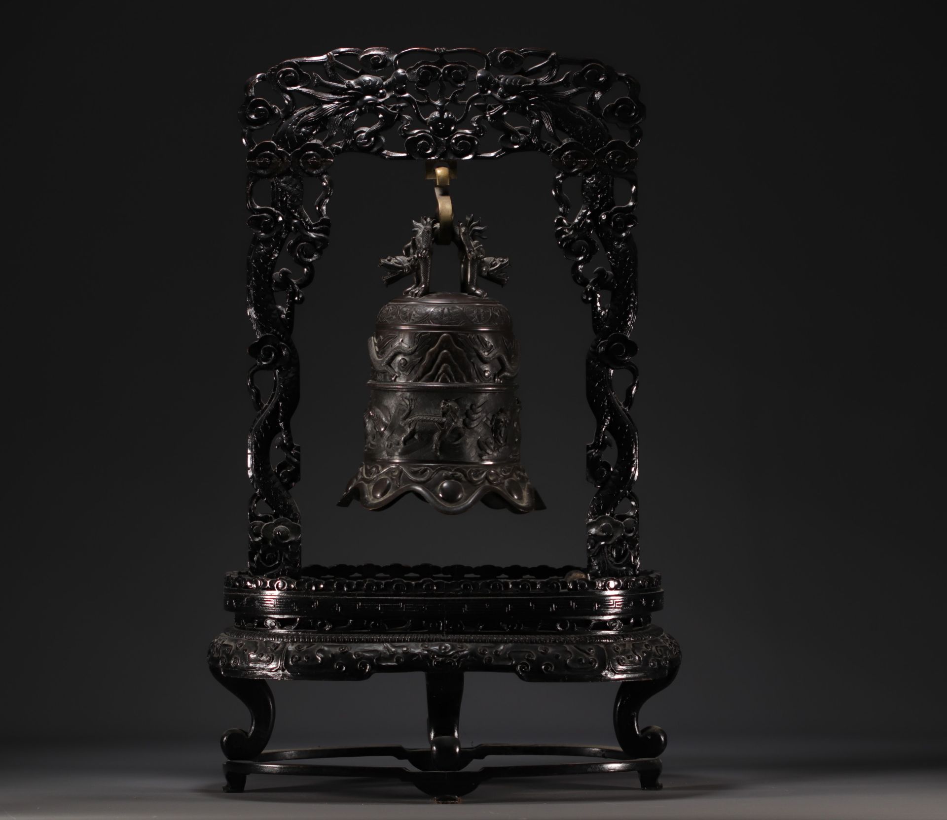 China - Bronze bell surmounted by a dragon, supported by a carved wooden base, circa 1900.