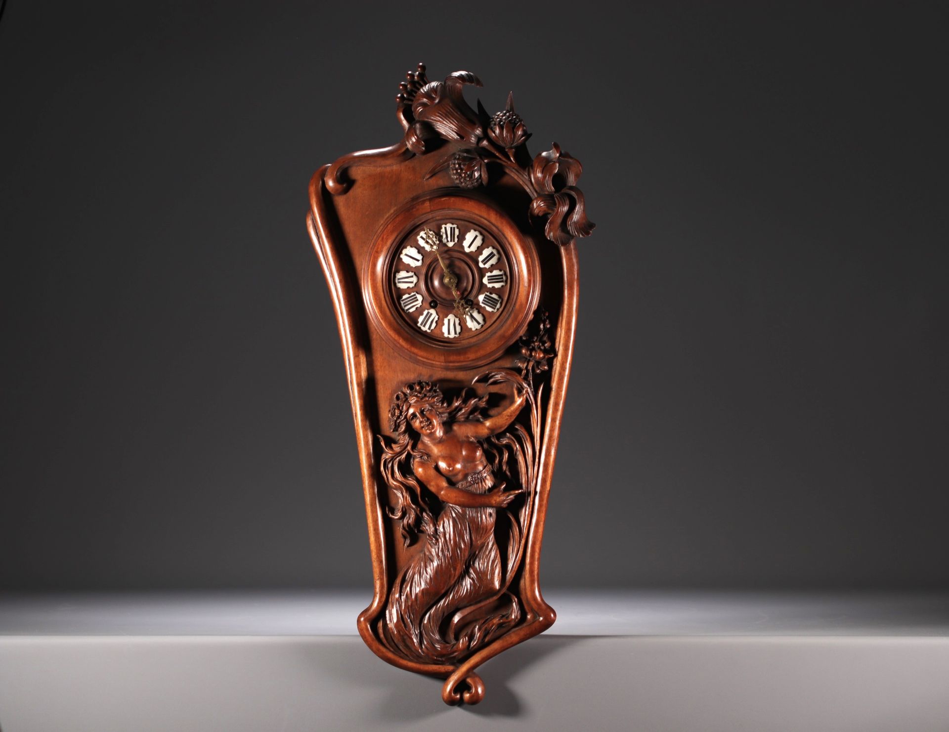 Art Nouveau clock in carved walnut with a half-dressed lady and floral decoration, enamel numerals, 