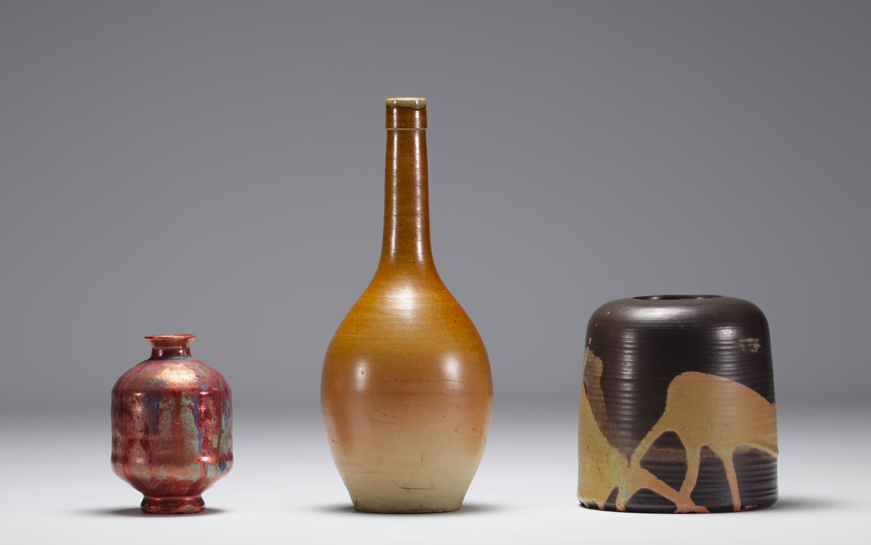 Set of three glazed ceramic pots, various markings.