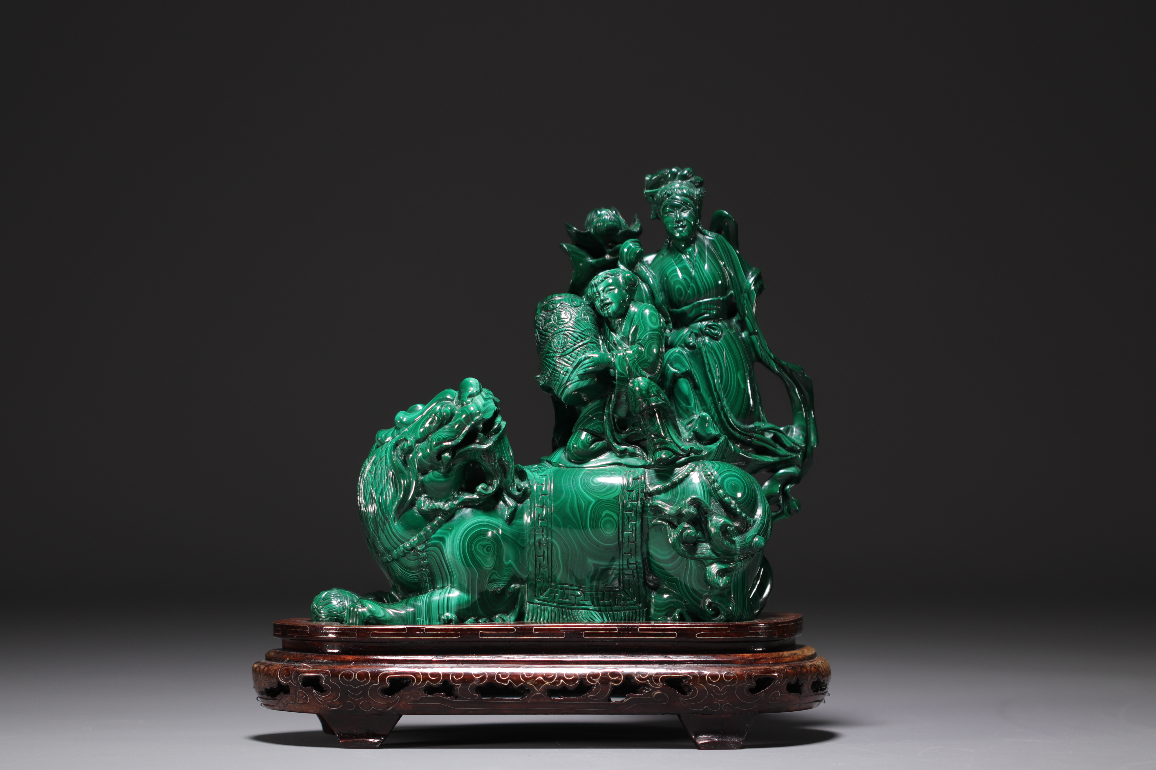 China - Malachite sculpture representing a Fo dog and characters, on a wooden base.