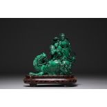 China - Malachite sculpture representing a Fo dog and characters, on a wooden base.