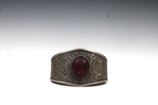 An Afghan Turkmen Silver Bangle with a Dyed Ruby Stone. Weight: 130g L: Approximately 5.8cm