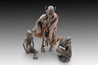 A Lot of African Tribal Wood Carvings of an Elder with a Leather Bag on his Back and 2 Sitting Peopl