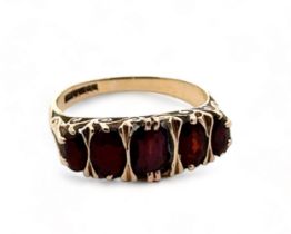 A hallmarked 9ct gold five stone garnet ring with scroll decoration, size O. 3.2g.