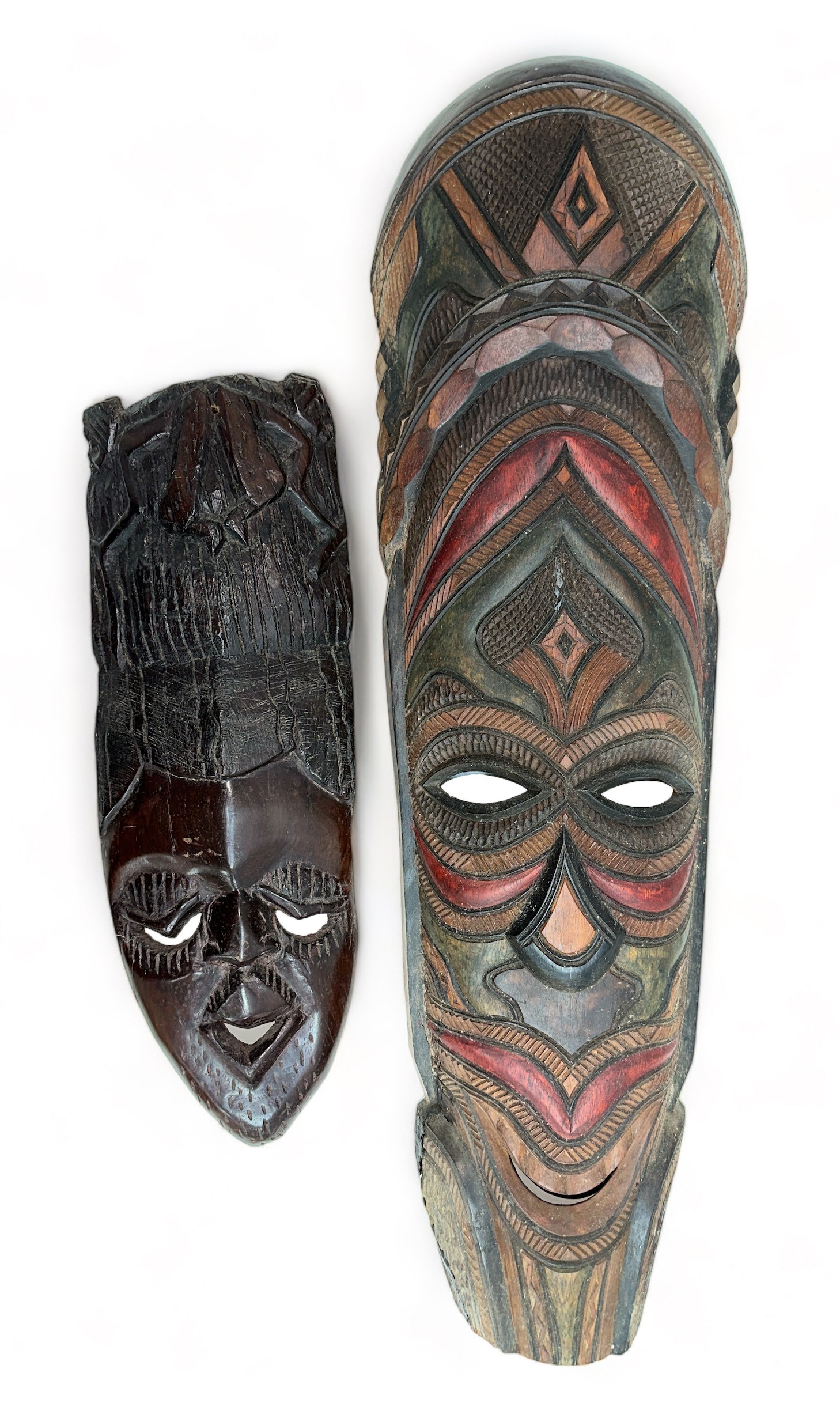 Pair of decorative wooden tribal masks, two designs, one larger and hand painted. Heights 75cm &