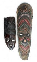 Pair of decorative wooden tribal masks, two designs, one larger and hand painted. Heights 75cm &