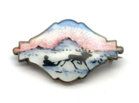 An Ivar Holth silver and enamel brooch depicting a reindeer pulling a figure on a sledge. Stamped '