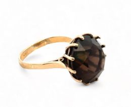 A smoky quartz ring set in 9ct gold, size O. Round smoky quartz is approx 14mm in diameter.