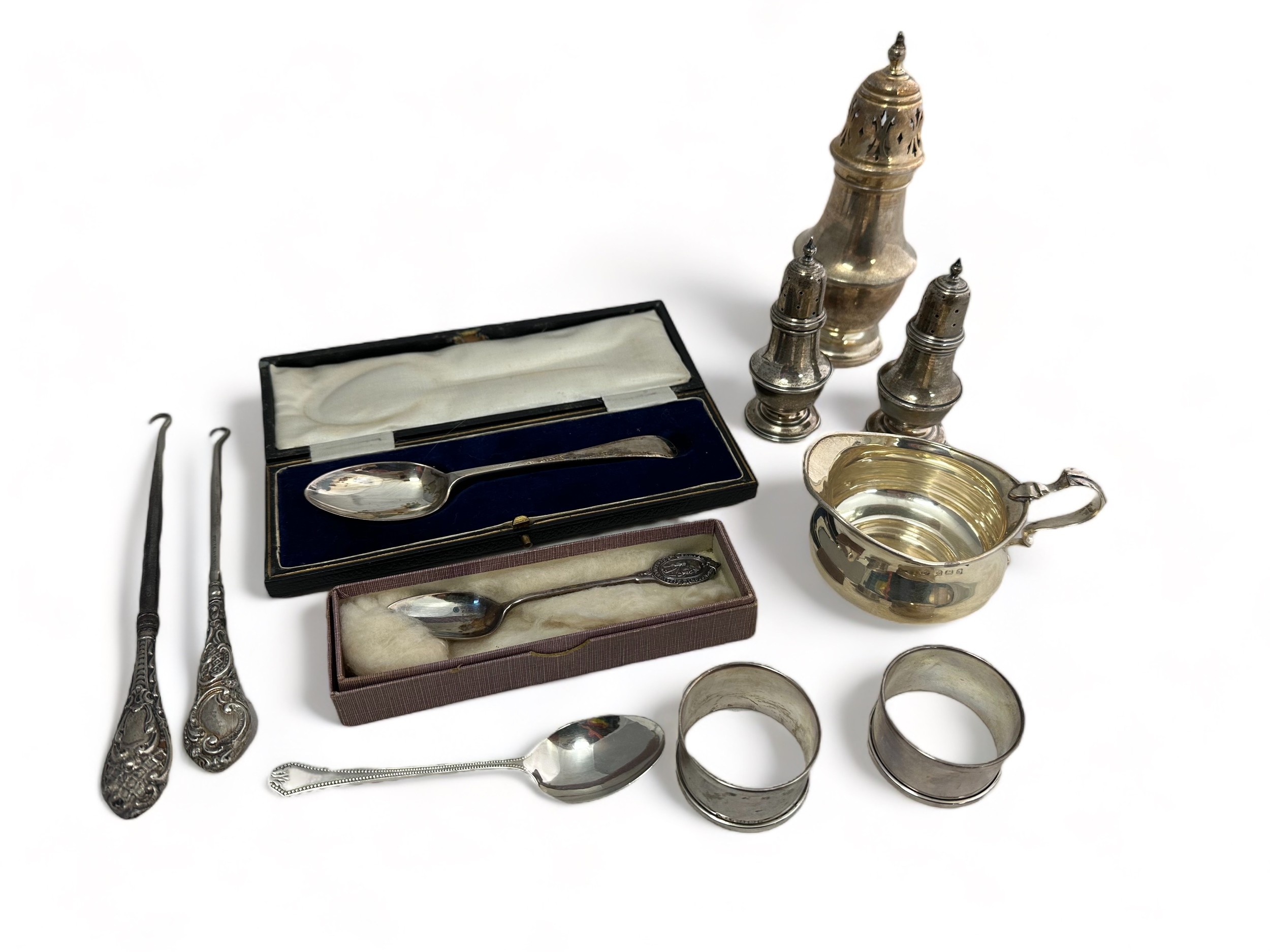 A range of hallmarked silver items, including a cream jug, sugar sifter, salt and pepper shakers,