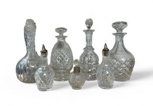 Range of cut glass decanters in varying sizes, two with silver cased toppers. Heights varying from