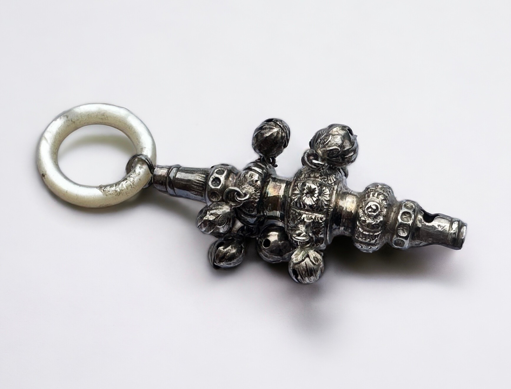 A silver rattle and whistle with mother of pearl teething ring. Chester hallmarks for maker CC.