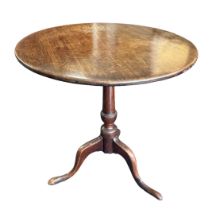 A late 18th Century mahogany tripod table. Having a circular hinged tilt top over a turned central