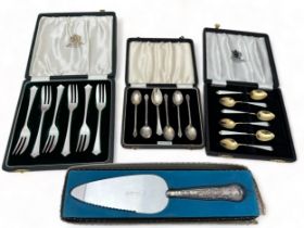 A cased set of silver tea spoons, a cased set of silver cake forks, a boxed cake slice with filled