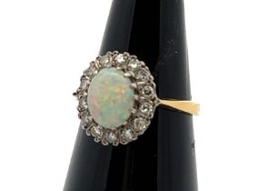 An 18ct yellow gold, opal and diamond ring. Opal (approx 9mm x 6mm) with full spectrum of colour