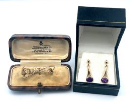 A pair of 9ct gold & amethyst pendant earrings and a yellow metal brooch in the form of the name '