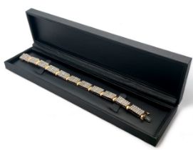 A 9ct gold and diamond bracelet. Each of the eleven main links is set with 35 diamonds. Length