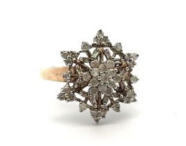 A 9ct gold and diamond ring with round and tapered baguette diamonds set in a snowflake design. Size