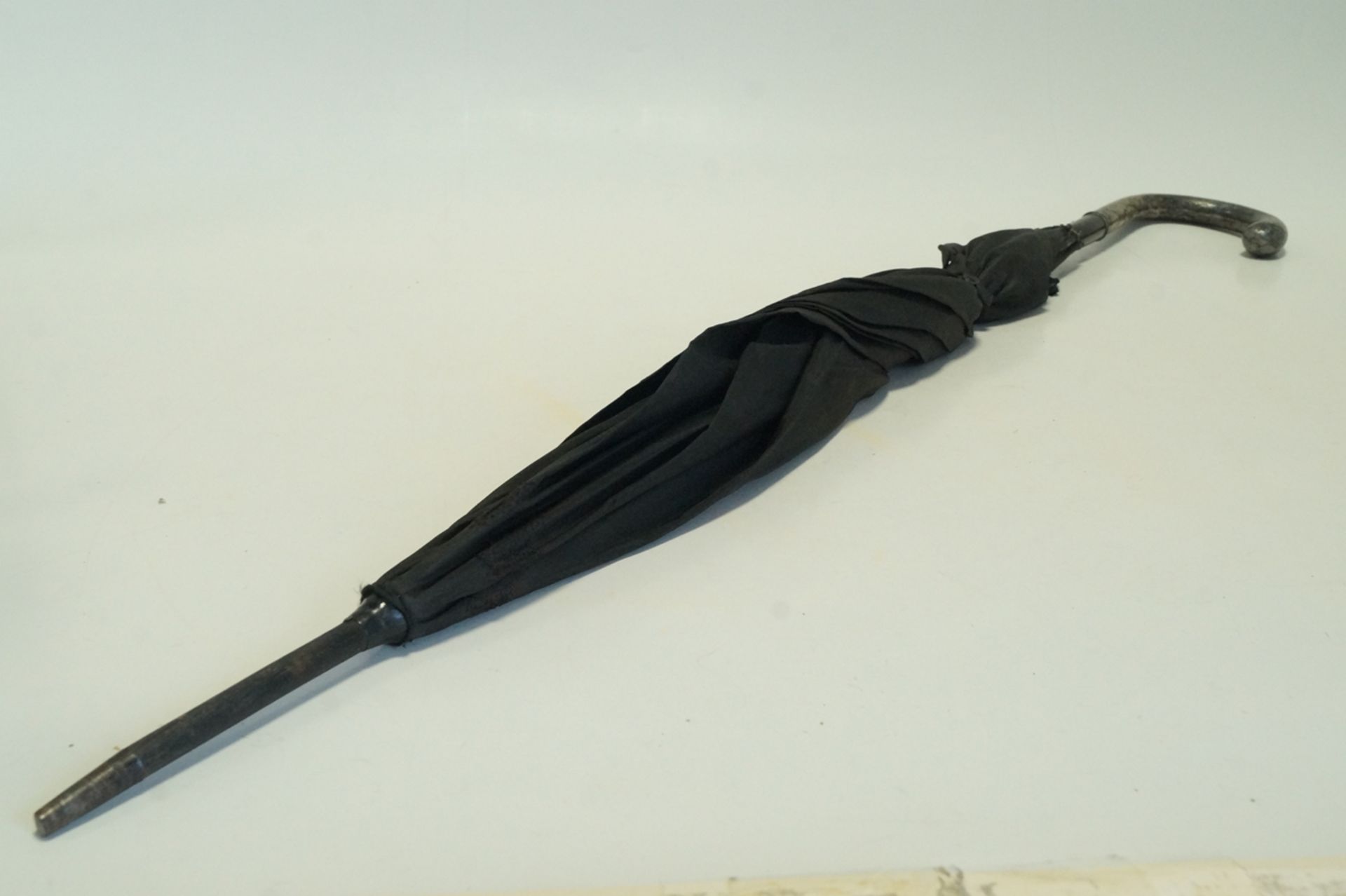 Alter Schirm mit Silbergriff und schwarzer Stoffbespannung; diese partiell alt repariert; Griffteil