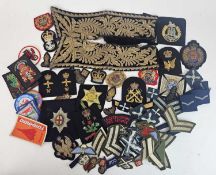 A large accumulation of British Army cap badges, buttons and cloth badges, together with a small