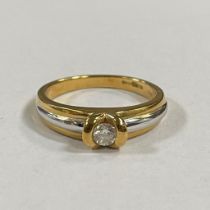 An 18ct yellow and white gold diamond solitaire ring. Featuring an estimated 0.17 carat round