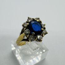 A sapphire and diamond cluster ring. Set in yellow metal stamped 750 to the shank. The oval mixed