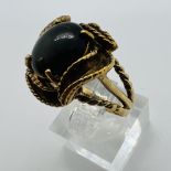 A black cabochon set 1970s style cocktail ring, Stamped "10K" and tests accordingly. Size N.